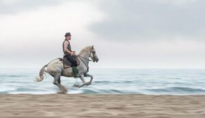 Photo en tirage limité. Série chevaux de camargue de Michèle Gabet Photographie. gardian sur son cheval au galop sur la plage