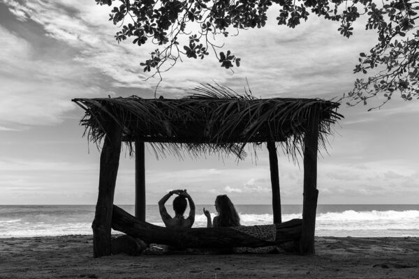 Photo de paysage de mer en tirage limité en noir et blanc. bord de mer avec 2 jeunes filles sous une paillote en contre jour. Michèle Gabet Photographie