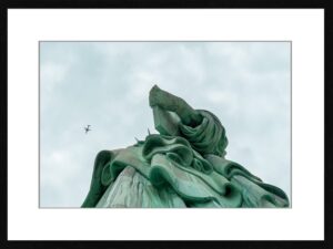 Photo en tirage limité. statue de la liberté en contre plongée - avion dans le ciel - new york. Michèle Gabet Photographie