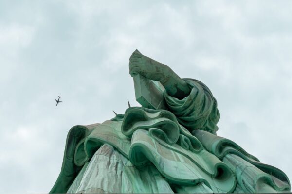 Photo en tirage limité. statue de la liberté en contre plongée - avion dans le ciel - new york. Michèle Gabet Photographie